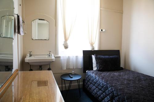 a small bathroom with a bed and a sink at Bank Hotel Dungog in Dungog