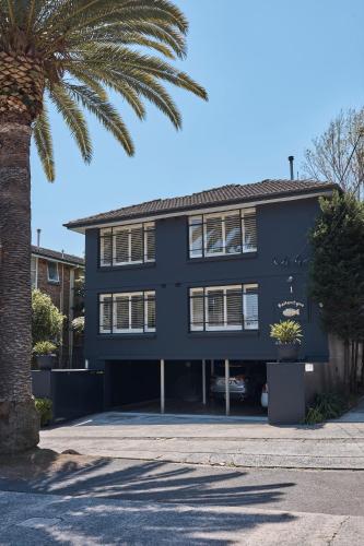 a black building with a palm tree in front of it at Ballantyne at Mosman Apartments in Sydney