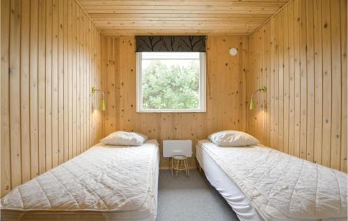 KnebelにあるBeautiful Home In Knebel With 3 Bedrooms And Wifiのウッドウォールと窓が備わるドミトリールームのベッド2台分です。
