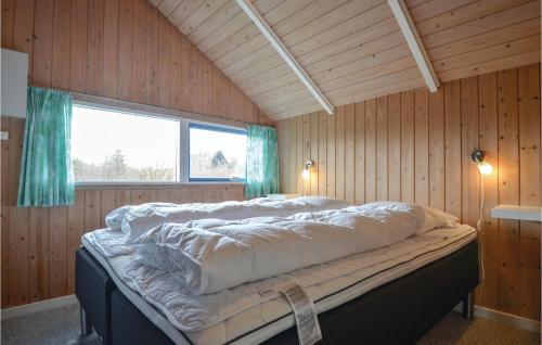 a large bed in a wooden room with a window at Awesome Home In Ebeltoft With 4 Bedrooms, Sauna And Wifi in Ebeltoft