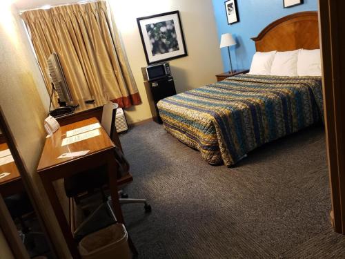 a hotel room with a bed and a desk and a desk at Red Carpet Inn-Macon in Macon