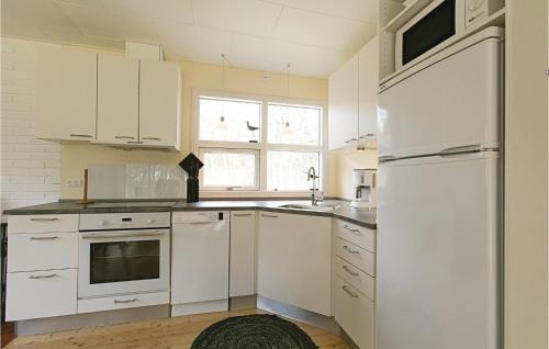 eine Küche mit weißen Schränken und einem weißen Kühlschrank in der Unterkunft Fyrreroden in Vester Sømarken