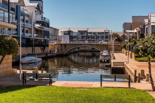 two benches sitting next to a river with a bridge at The Hutt on Mandurah Marina in Mandurah