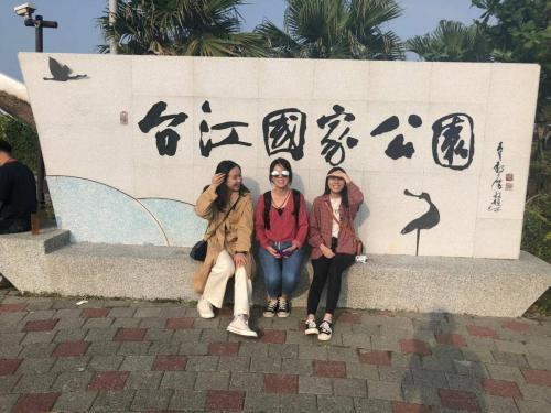 three women sitting in front of a wall with signs at mydeer backpacker in Tainan