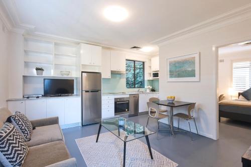 een keuken en een woonkamer met een tafel en een bank bij Ballantyne at Mosman Apartments in Sydney
