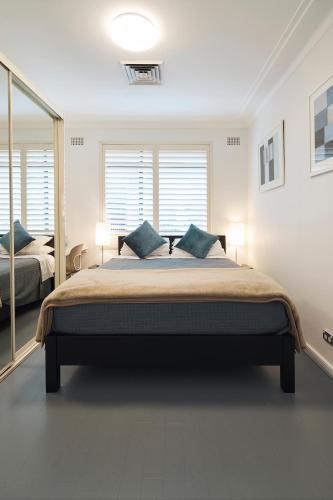 a bedroom with a large bed with blue pillows at Ballantyne at Mosman Apartments in Sydney