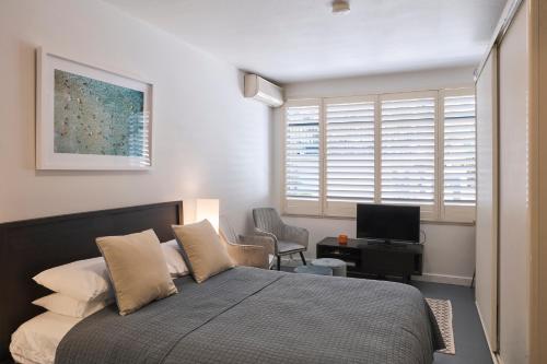 a bedroom with a bed and a desk with a television at Ballantyne at Mosman Apartments in Sydney