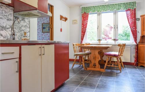 una cocina con mesa y sillas y una cocina con armarios blancos. en Nice Home In Gamleby With House A Panoramic View en Gamleby