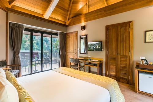 a bedroom with a large bed and a balcony at River Kwai Resotel in Sai Yok