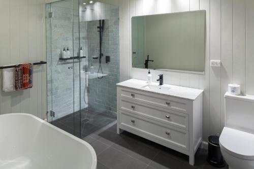 a white bathroom with a sink and a shower at The Manse on Ebden in Kyneton