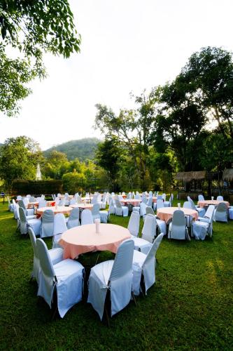 a group of tables and chairs with white tables and chairs at River Kwai Resotel in Sai Yok