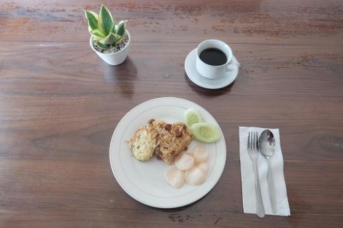 Hotel Olympic Semarang by Sajiwa في سيمارانغ: صحن طعام مع فنجان قهوة وصحن فاكهة