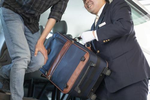 a man is helping another man with a suitcase at Hotel Marroad Karuizawa in Karuizawa