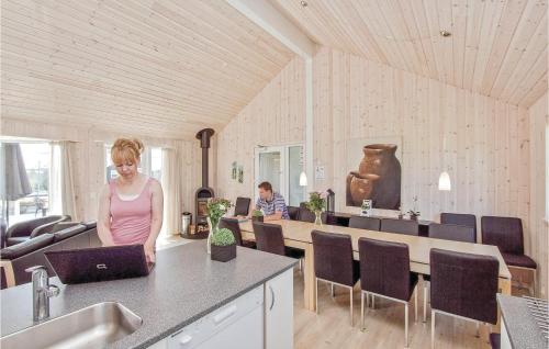 a woman standing in a kitchen with a laptop at Nice Home In Idestrup With Sauna in Marielyst