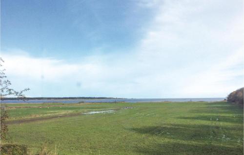 a green field with the ocean in the background at Three-Bedroom Holiday Home In Orsted in Udbyhøj
