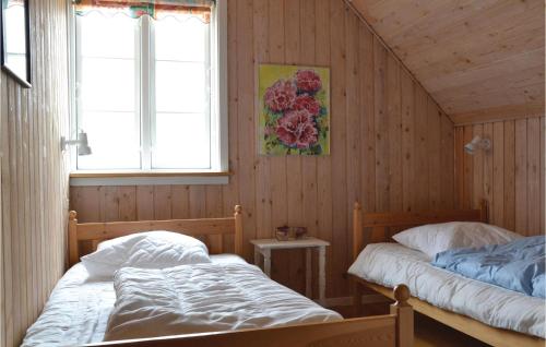 two beds in a room with wooden walls and two windows at Beautiful Home In Fan With Sauna in Fanø