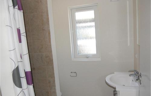 La salle de bains est pourvue d'un lavabo, de toilettes et d'une fenêtre. dans l'établissement Nice Home In Idestrup With Sauna, à Bøtø By