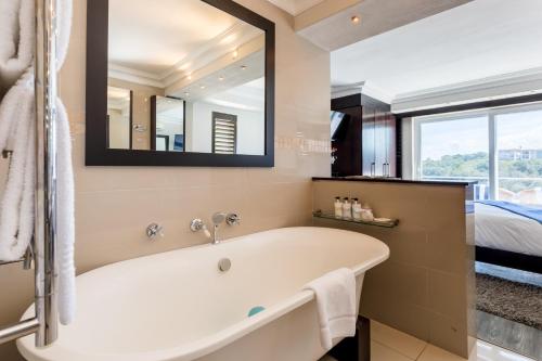 a bathroom with a tub and a bed and a mirror at Head over Hills in Knysna
