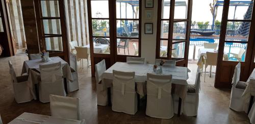a room with white tables and chairs and windows at Hotel Philoxenia in Masouri