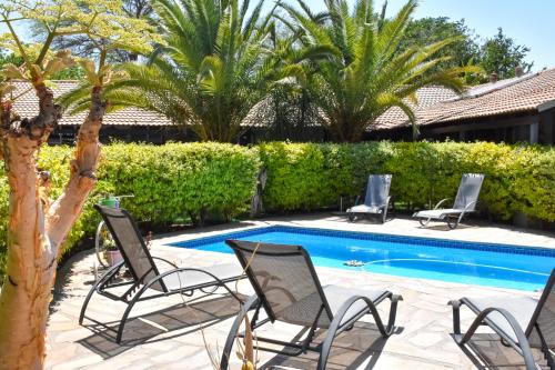 a group of chairs sitting next to a swimming pool at Kamaku Guesthouse cc in Otjiwarongo
