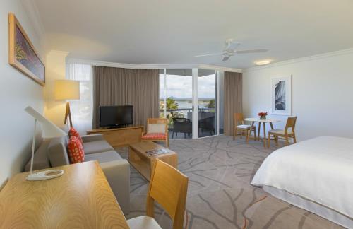a hotel room with a bed and a living room at Sofitel Noosa Pacific Resort in Noosa Heads