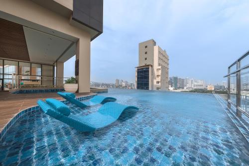 宿霧市的住宿－Citadines Cebu City，一座带两把蓝色椅子的游泳池,位于一座建筑的顶部