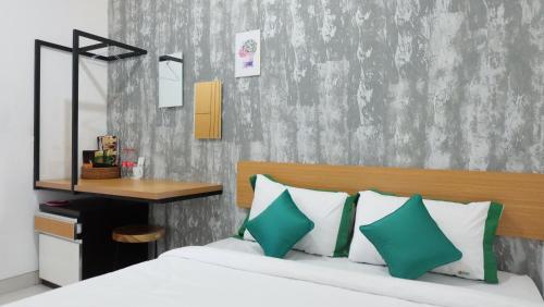 a bedroom with a bed with green and white pillows at Hotel Jogja Kili Suci By Simply Homy in Yogyakarta