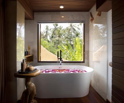 a bath tub in a bathroom with a window at Green Field Resort Ubud in Ubud