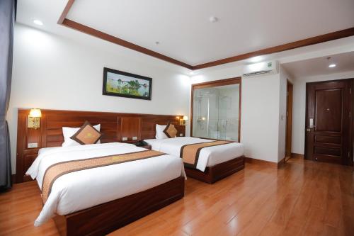 a hotel room with two beds and a mirror at Bảo Hân Hotel in Ha Long