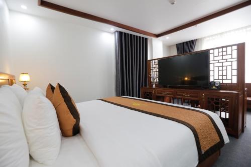 a hotel room with a bed and a flat screen tv at Bảo Hân Hotel in Ha Long