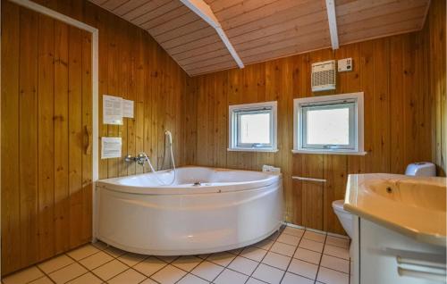 ロモ・キルケビーにあるGorgeous Home In Rm With Saunaの木製バスルーム(白い大型バスタブ、シンク付)
