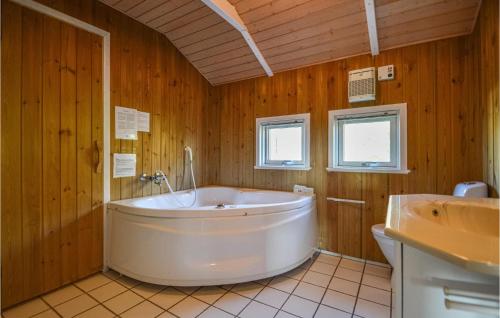 a large white tub in a wooden bathroom with a sink at Holiday Home Kromosevej Rømø Denm in Rømø Kirkeby