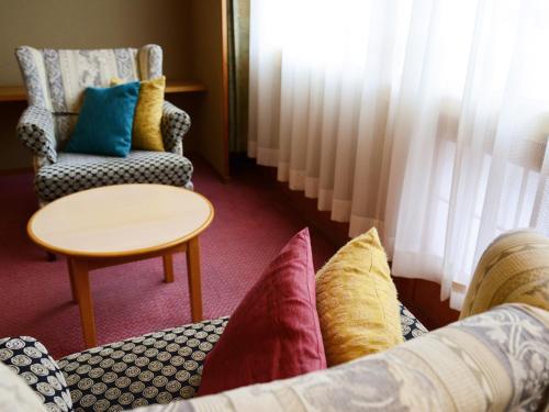 a room with a couch and a chair and a table at Hanamomiji in Jozankei
