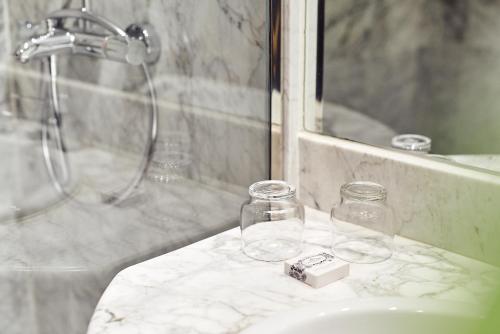 a bathroom with a sink and glass jars and a shower at Occidental León Alfonso V in León