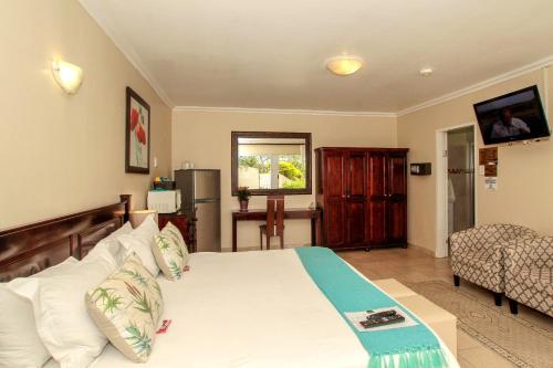 um quarto com uma grande cama branca e uma cadeira em Chartwell Guest House em Durban