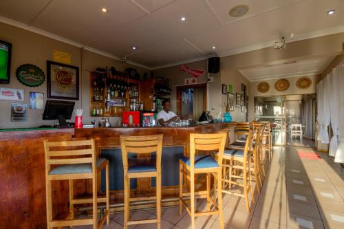 a bar with wooden stools in a restaurant at The Ridge Guesthouse in Richards Bay