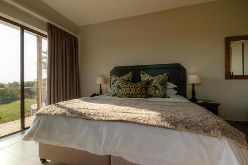 a bedroom with a large bed and a large window at The Ridge Guesthouse in Richards Bay