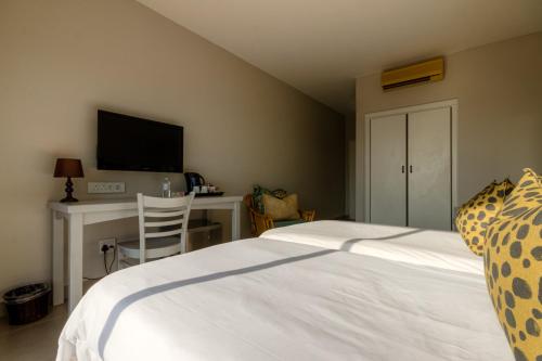 a bedroom with a bed and a desk with a television at The Ridge Guesthouse in Richards Bay