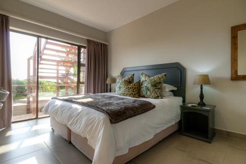 a bedroom with a large bed and a large window at The Ridge Guesthouse in Richards Bay