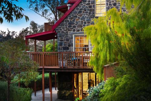 a stone house with a deck and a porch at Bluegums Retreat in Hepburn Springs