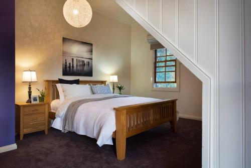 Un dormitorio con una cama grande y una escalera. en Bluegums Retreat, en Hepburn Springs