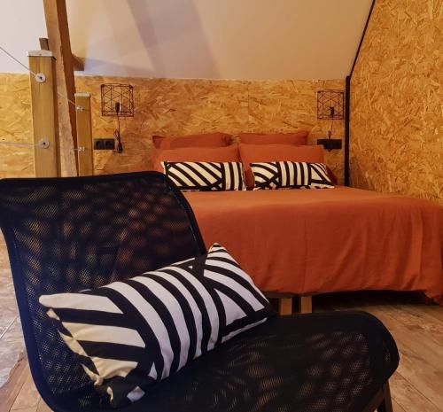 a bedroom with a bed and a black chair with a pillow at Odyssée - Chambre d'hôtes avec spa et sauna privés in Zeggers-Cappel