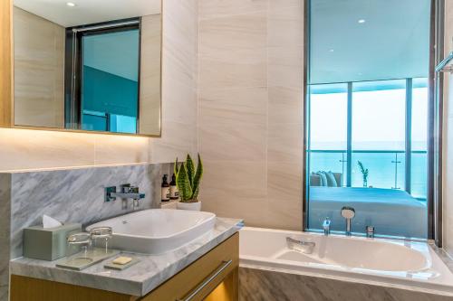 a bathroom with a sink and a tub and a window at Prince Hotel Da Nang - Formerly Sel de Mer Hotel & Suites in Danang