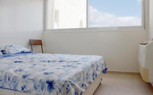 a bedroom with a blue and white bed and a window at Rachel imenu Duplex Apartment Amazing sea view in Ashdod