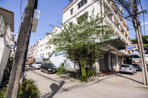 een straat met auto's geparkeerd voor een wit gebouw bij SLT Apartment Bangkok in Bangkok