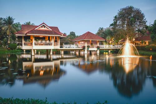 a pond in front of a house with a fountain at Sofitel Angkor Phokeethra Golf & Spa Resort in Siem Reap