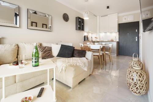 una sala de estar con un sofá y una mesa en Apartament GOLD Gardenia Dziwnów, en Dziwnów