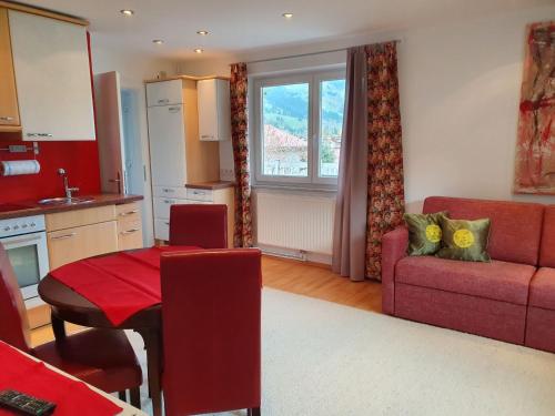 cocina y sala de estar con sofá rojo y mesa en Appartements Strasser Angelika, en Westendorf