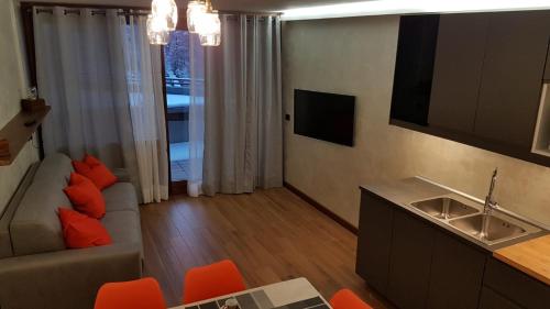 a living room with a couch and a kitchen with orange chairs at Orange Fox Cervinia apartment Vda Vacanze in Vetta CIR 0185 in Breuil-Cervinia