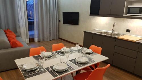 a dining room table with chairs and a kitchen at Orange Fox Cervinia apartment Vda Vacanze in Vetta CIR 0185 in Breuil-Cervinia